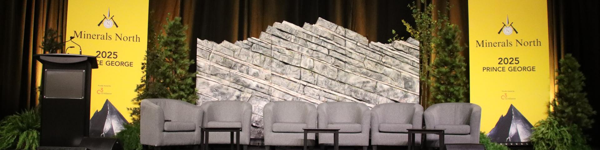 Minerals North Conference 2025 Chairs with a podium and pop up banners on a stage with a rock backdrop
